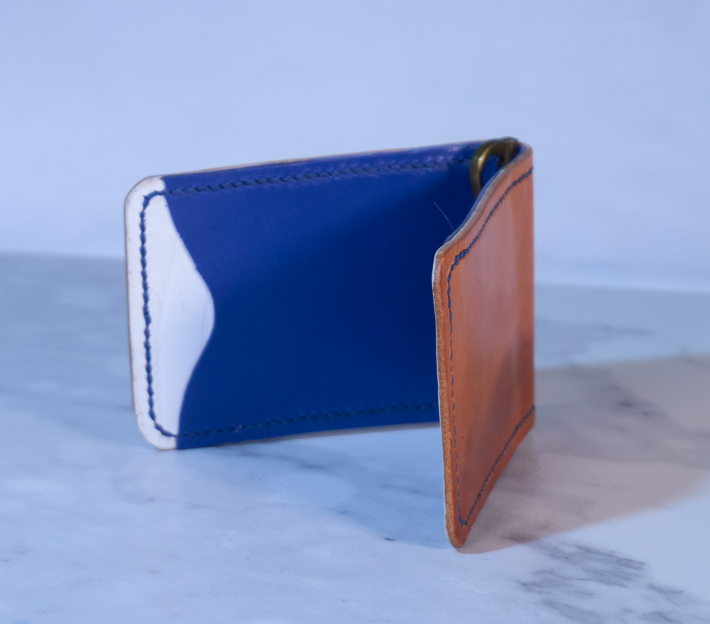 Money clip with orange exterior, white lining and blue pockets