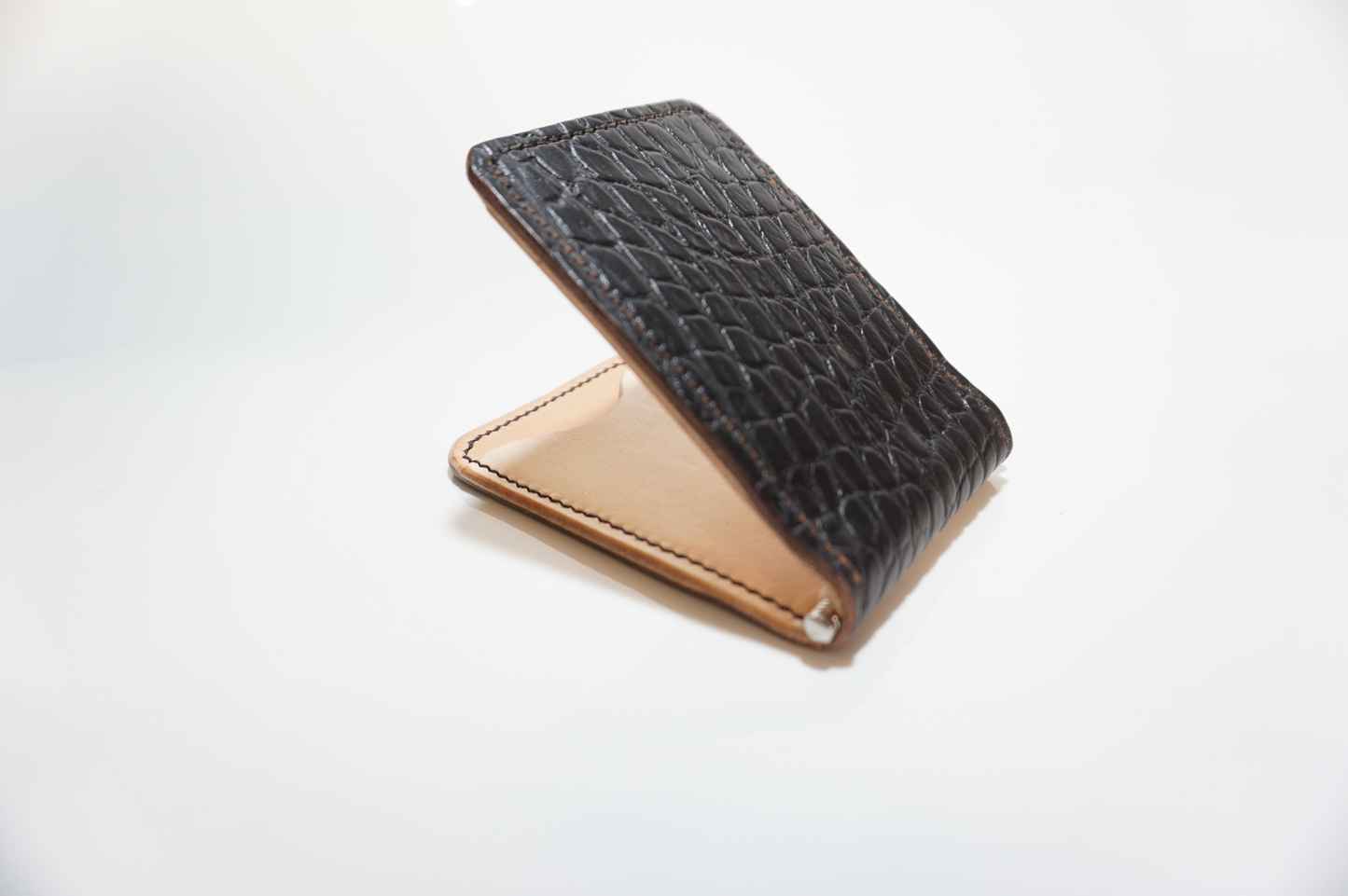 Texture highlight for money clip with black gator embossed exterior, natural lining, tan pockets, and silver money clip