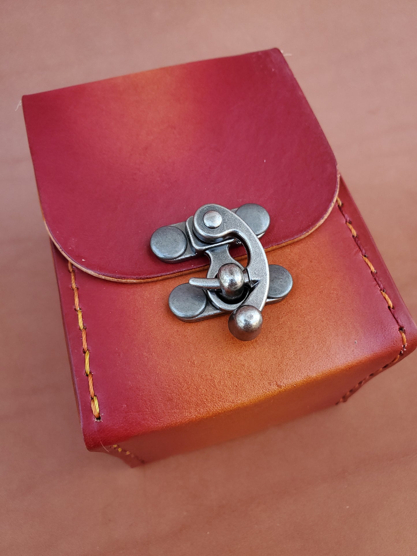 Front of a handstitched red box for playing cards with swing latch.
