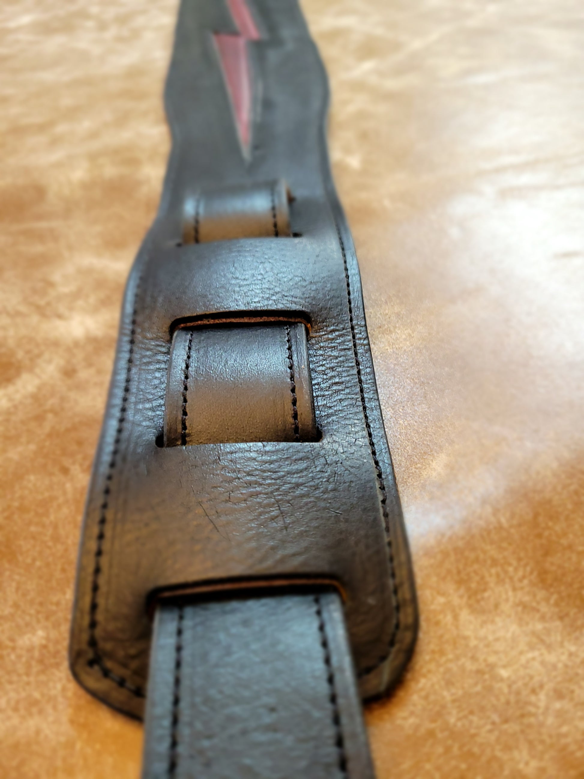 Heavy black leather lined guitar strap highlighting adjustment strap