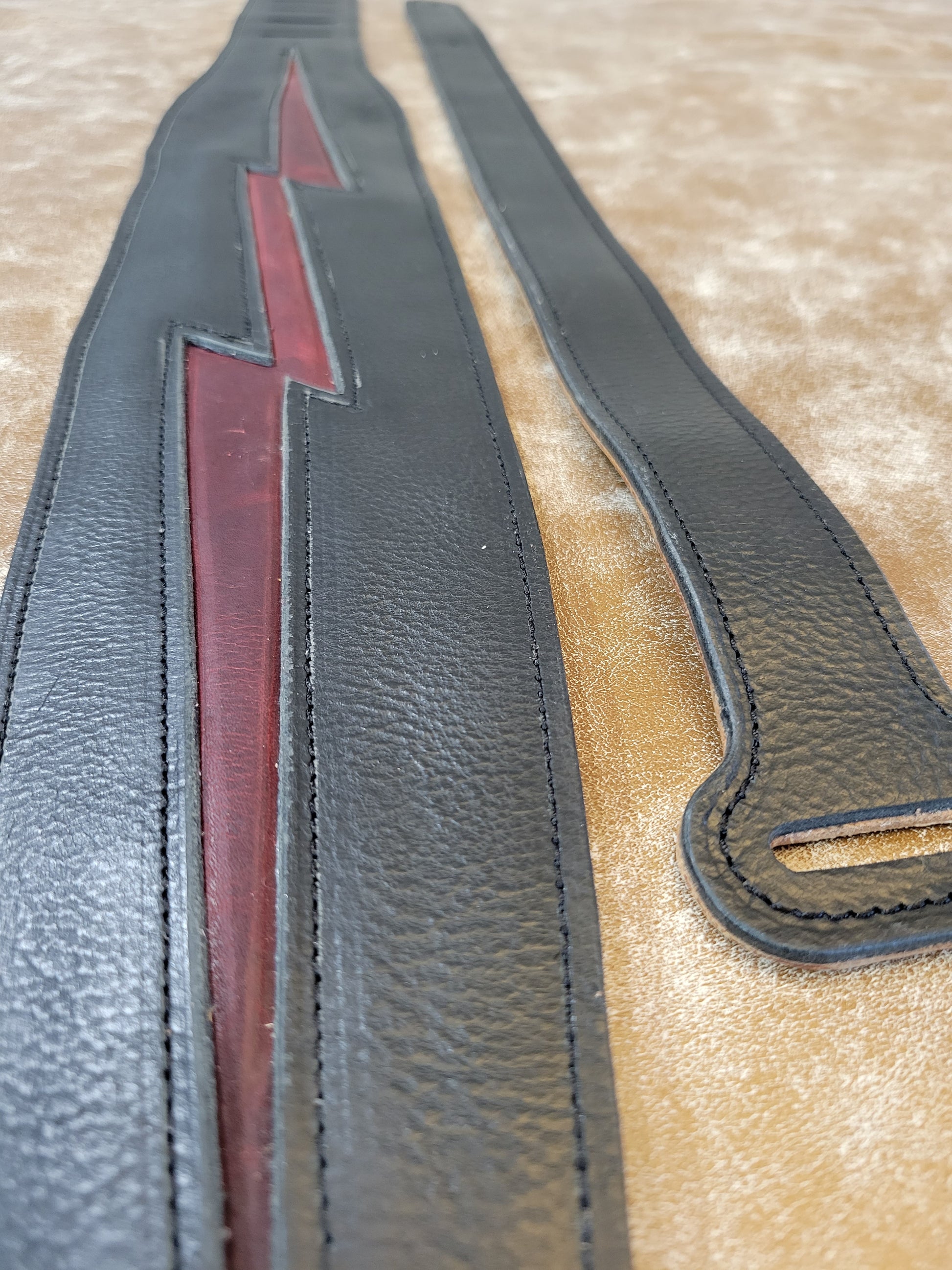 Heavy black leather lined guitar strap with red lightning padded inlay. Photo shows strap and adjustment strap.