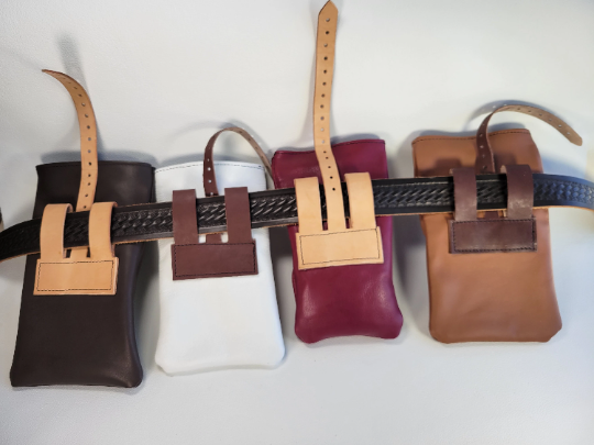 Four small leather rolltop pouches showing brown, red, white, and tan. Photos shows the blets hanging on a 1.5 inch belt.