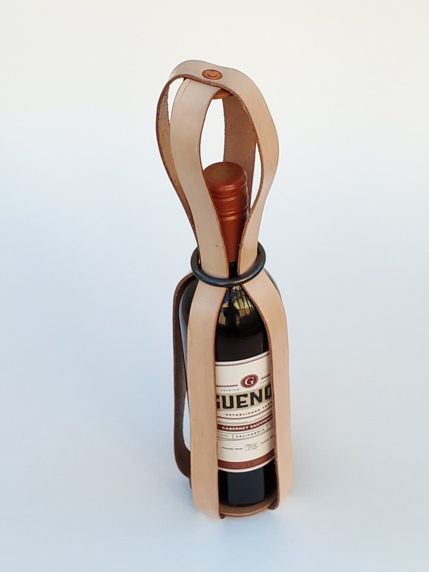 Wine bottle holder made from top grain leather straps on a white background.