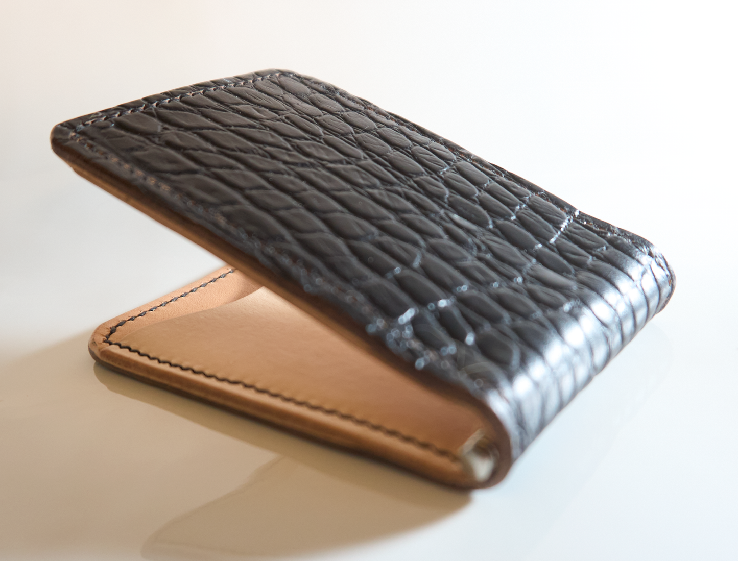 Closeup detail of money clip with gator embossed cow leather exterior, natural interior and tan card pockets showing texture highlights