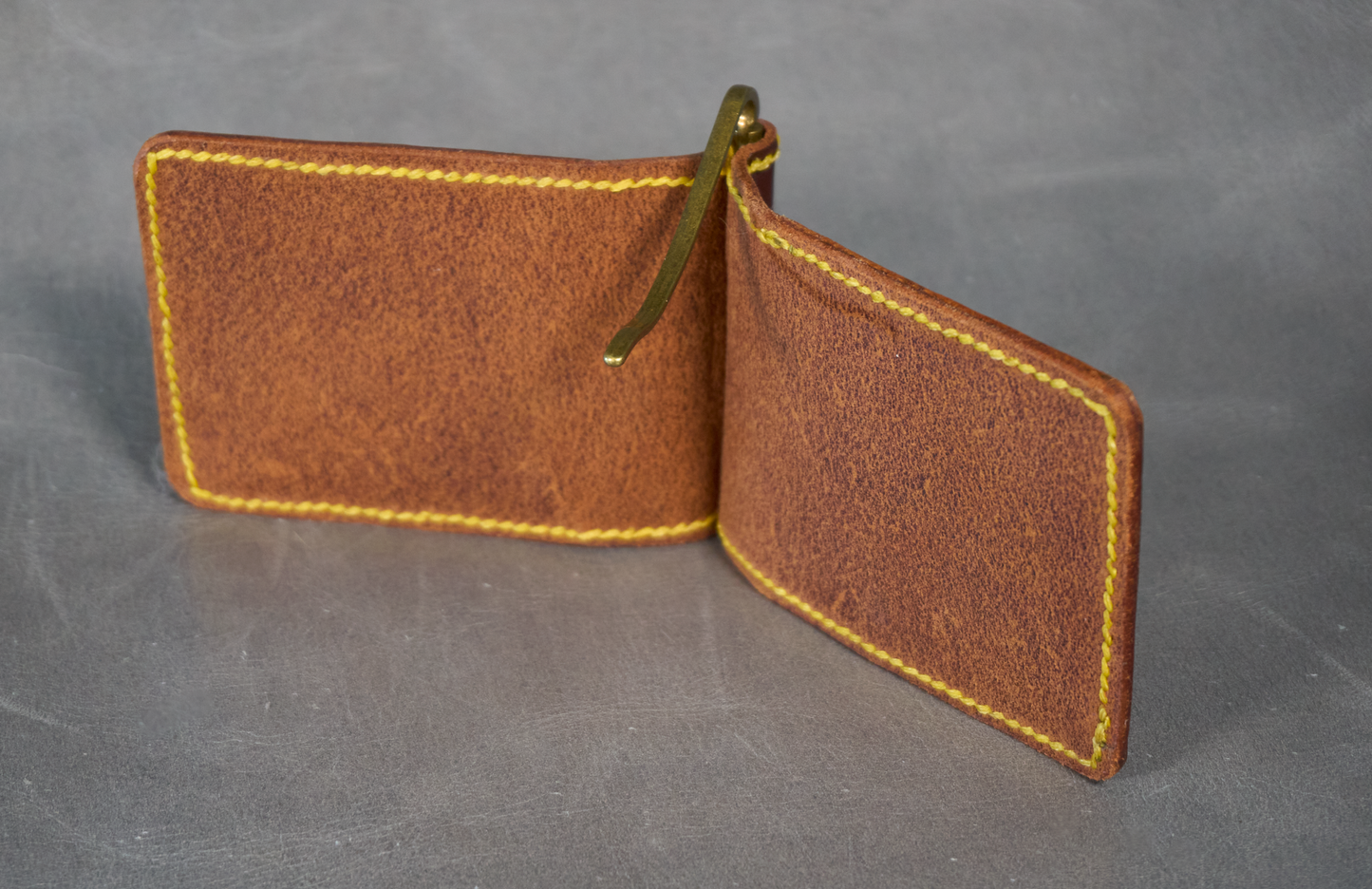 Interior of unlined money clip with no pockets, contrasting yellow stitching, and brass money clip