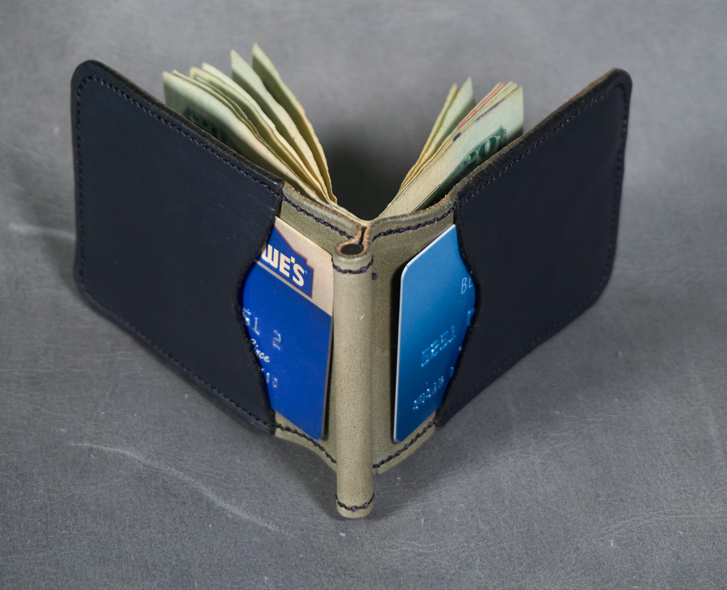 Detail of soft grey money clip with black exterior pockets showing card pockets and cash